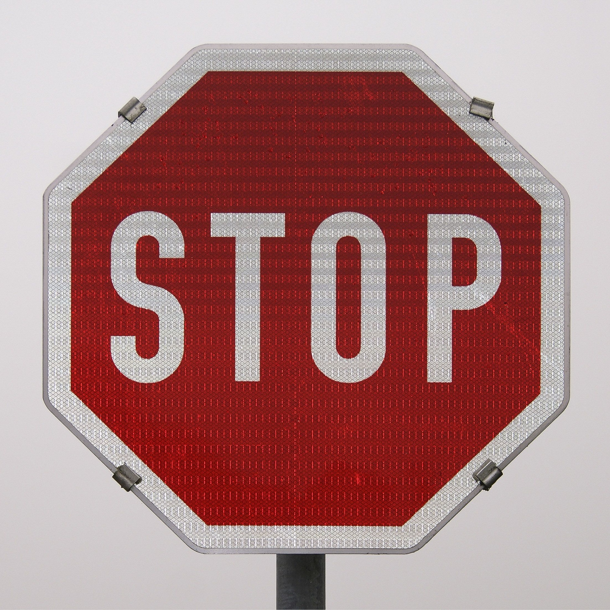 Rotes Stopschild mit weißer Schrift auf grauem Hintergrund.